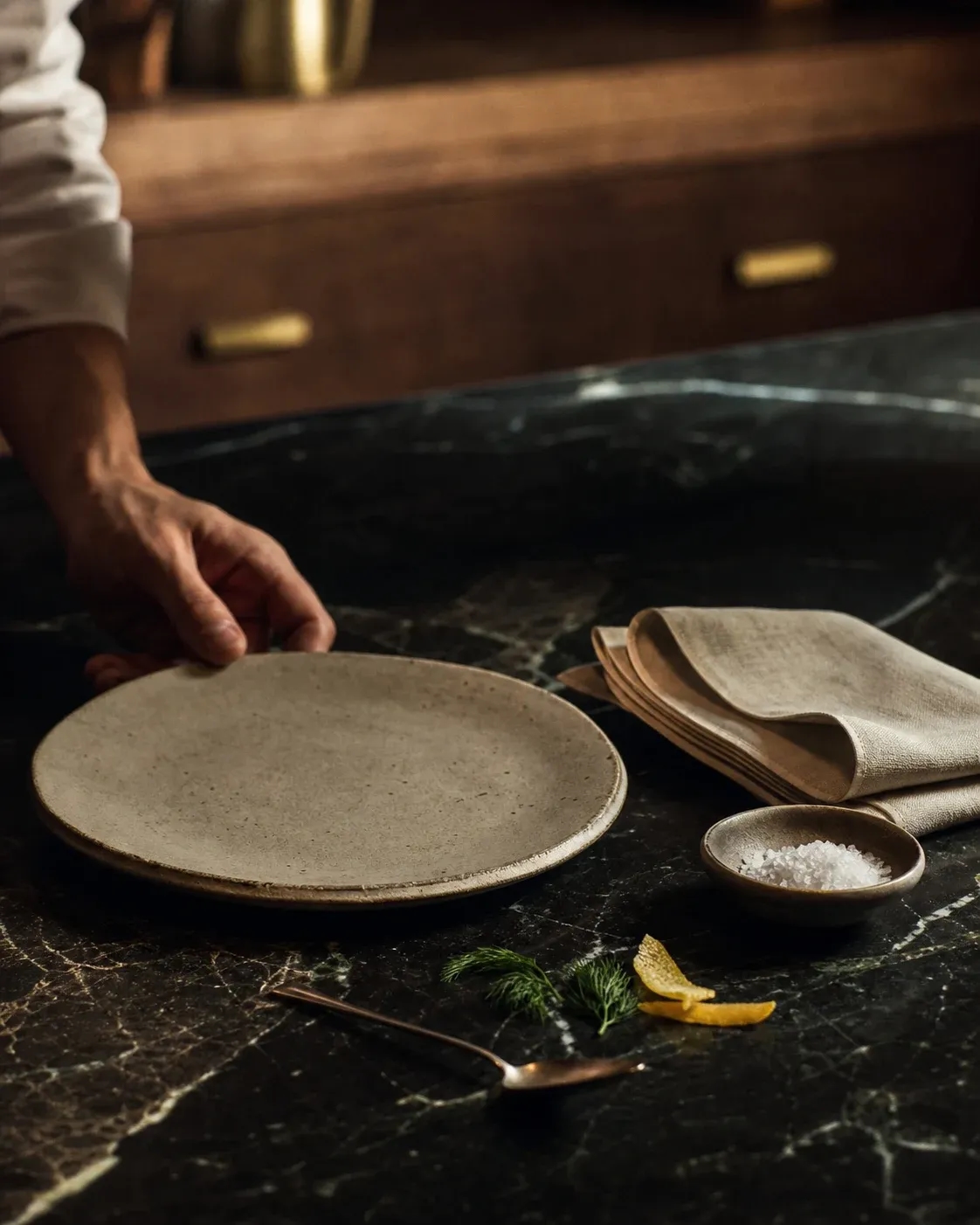 A chef completing a restrained mise en place at a black marble counter