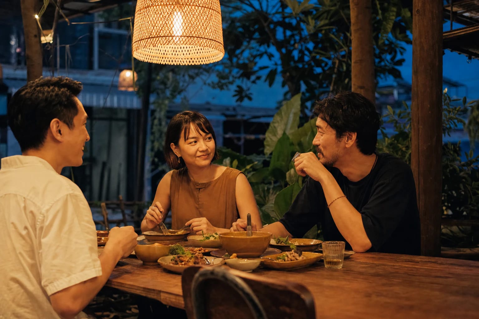 People enjoying several small dishes together around an evening table.