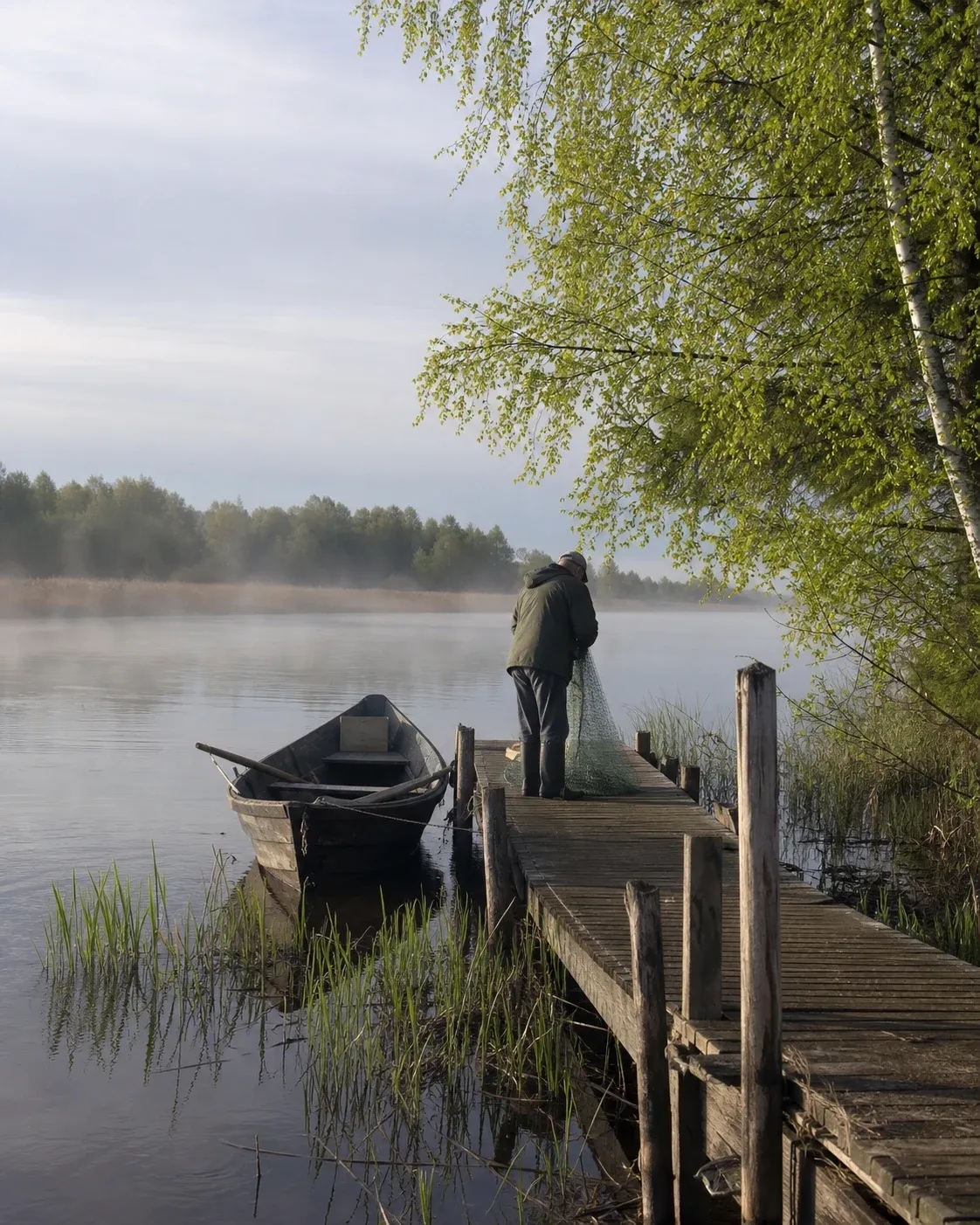 A local fisher preparing a net beside a Latvian river in spring