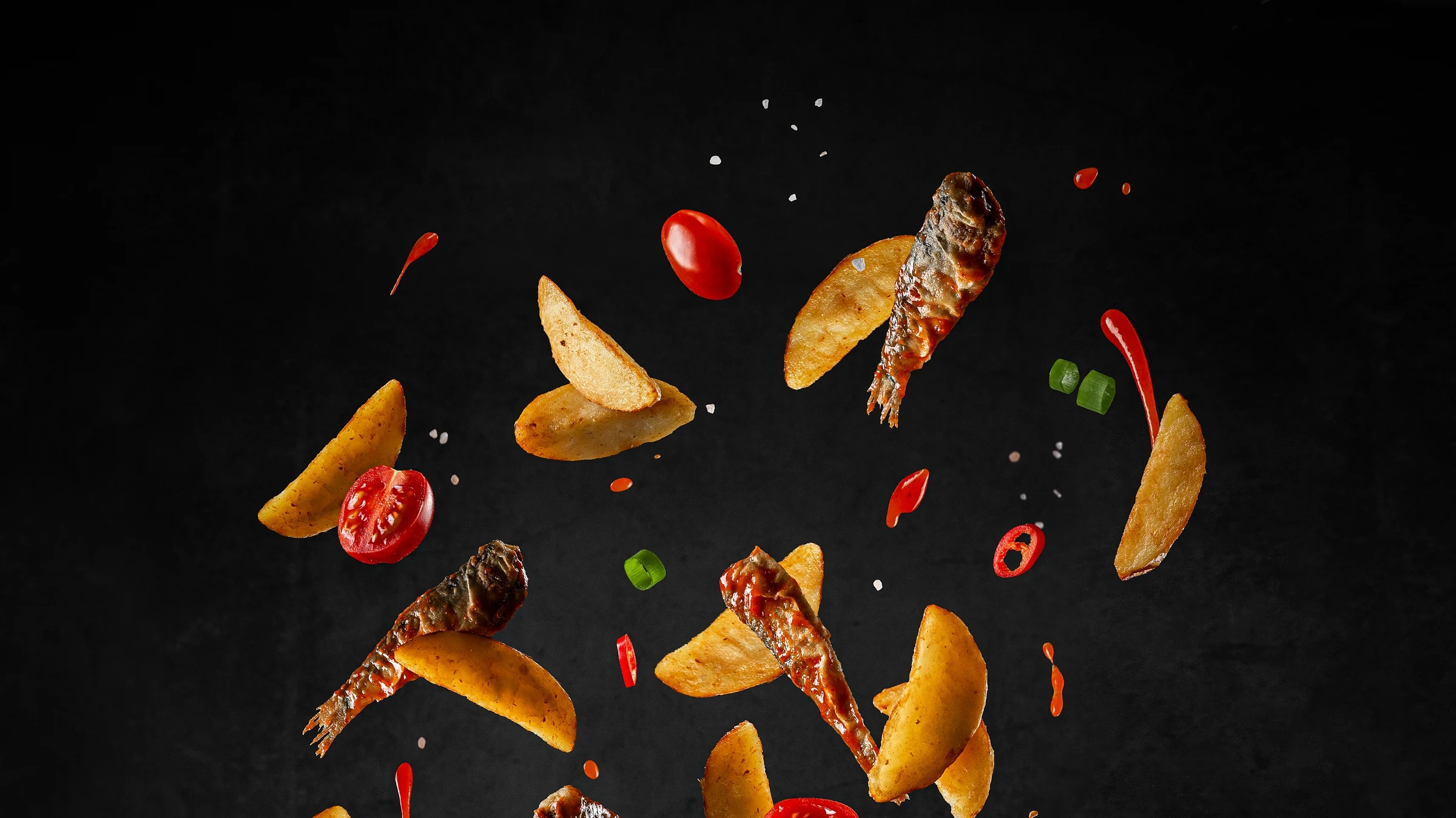 Sprats, potato wedges and fresh vegetables arranged in a dynamic culinary composition