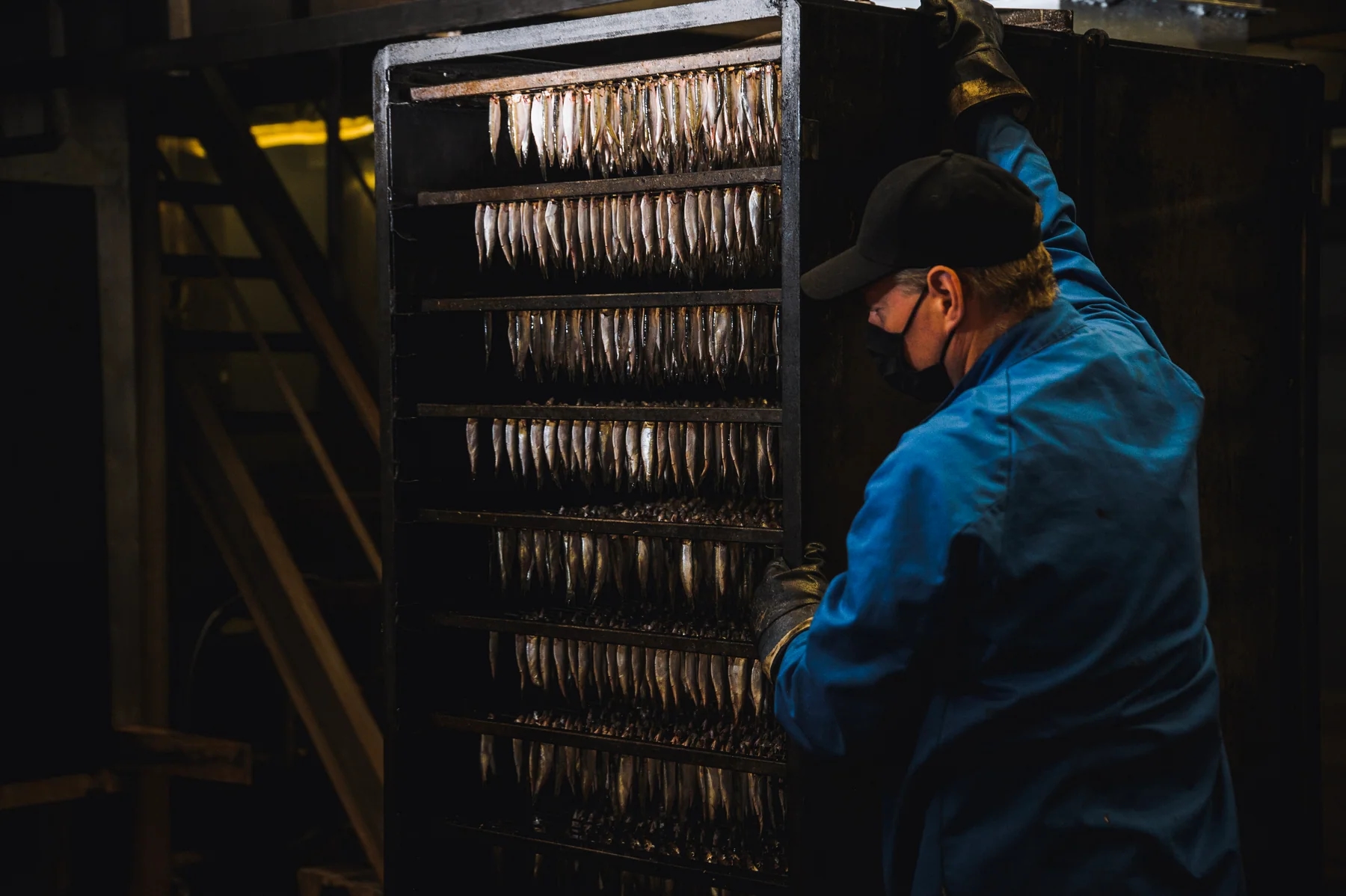 A Diplomats specialist inspecting fish on smoking racks